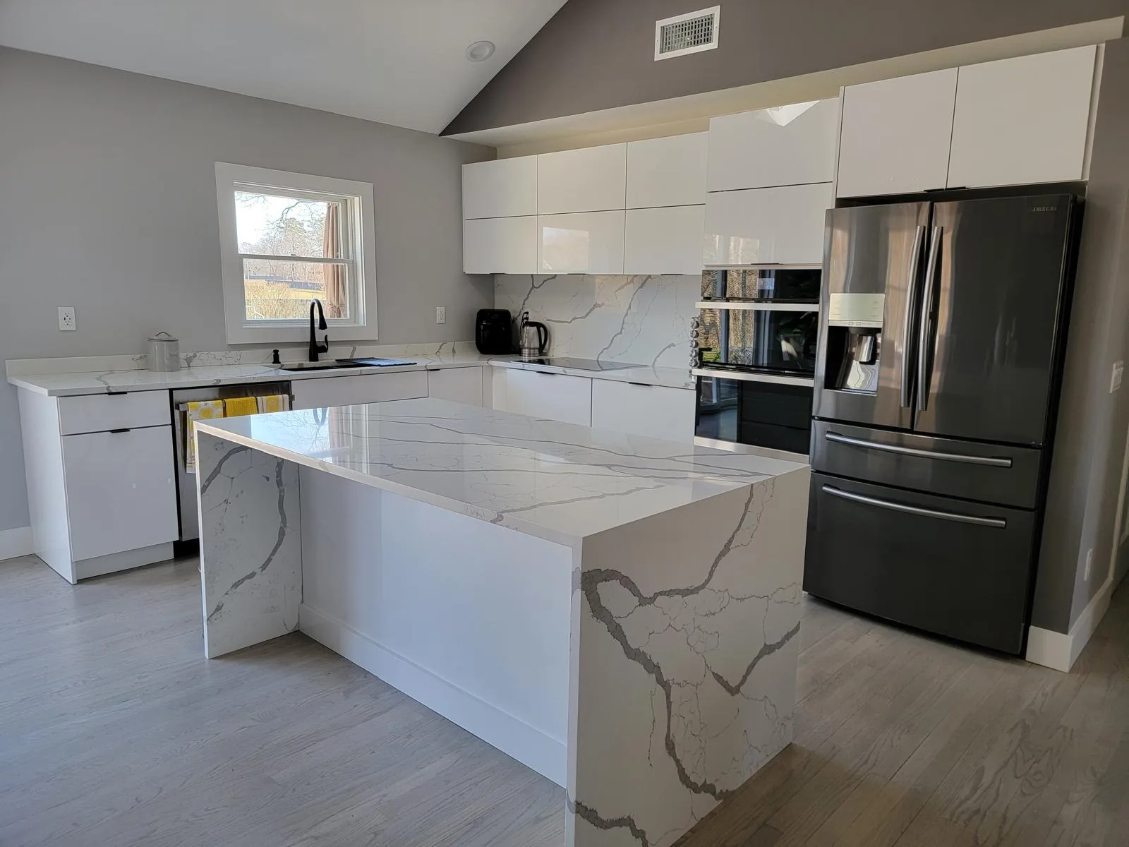 Immaculate modern kitchen with a marble waterfall island and gloss white cabinetry
